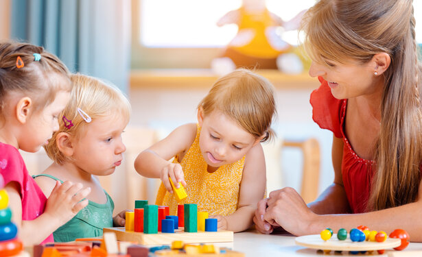 Group of children and teacher playing in kindergarten